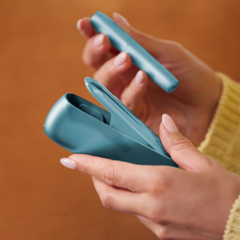 Rokas, kas izņem IQOS ORIGINALS DUO turētāju no lādētāja.