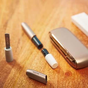 IQOS 3 и чистящий инструмент лежат на столе.