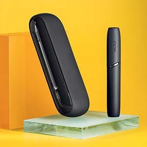 IQOS 3 черного цвета на желтом фоне.