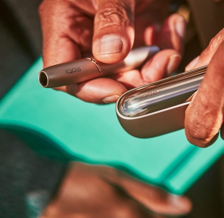 Руки держат устройство IQOS ILUMA цвета Golden Khaki