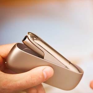 Руки держат зарядное устройство IQOS 3 DUO.