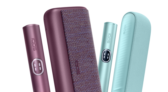 IQOS ILUMA i PRIME Garnet krāsā un IQOS ILUMA i ierīce  Breeze blue krāsā uz tirkīza fona.