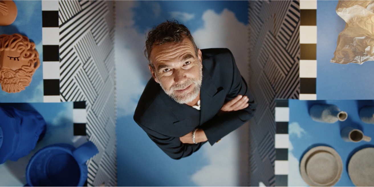 Dizainers Stefano Seletti krāsainā fona priekšā ar pogu „Atskaņot video”