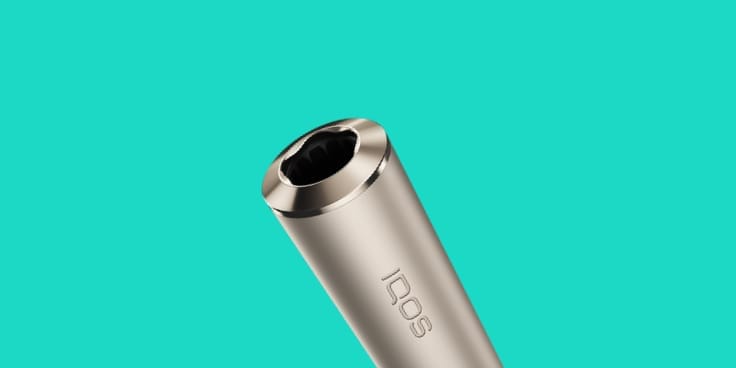 IQOS ILUMA turētājs  Pebble Beige krāsā un uz tirkīza fona